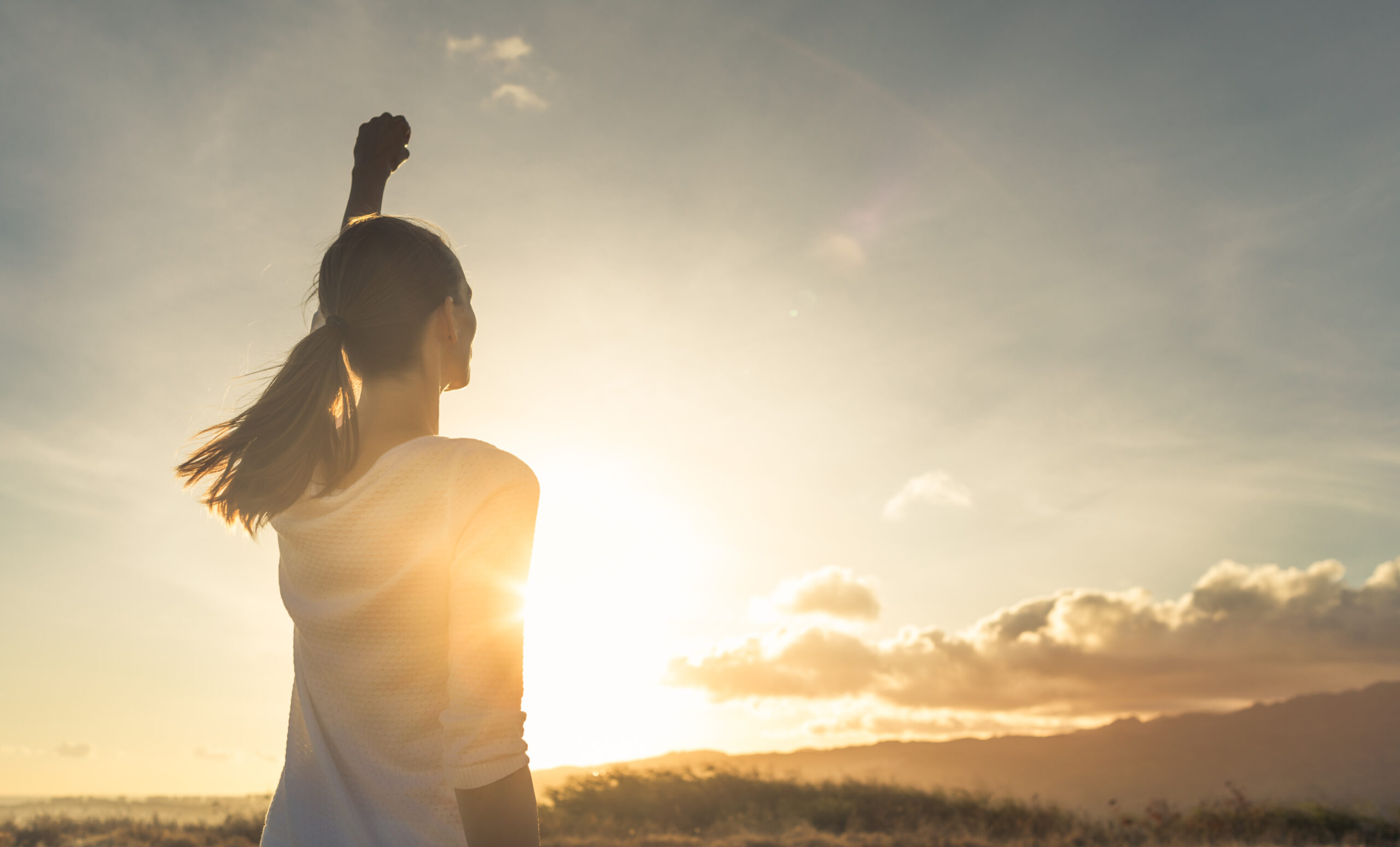 Young female outdoors with fist in the air feeling strong and co
